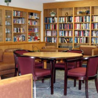 A cozy library room with bookshelves, a round table, and comfortable chairs.