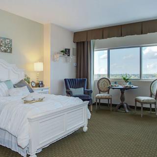 A well-decorated hotel room with a bed, seating area, and large window.