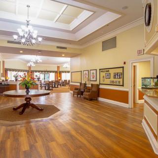 A spacious and elegantly designed lobby area with wood flooring, a chandelier, and comfortable seating.
