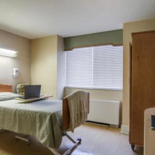 A well-lit hospital room with a single bed and a window.