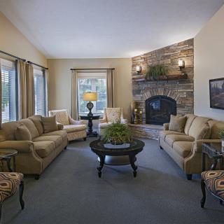 A cozy living room with a stone fireplace, sofas, and elegant decor.