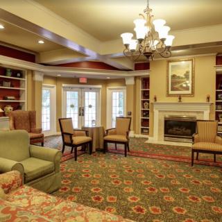A cozy living room with elegant furnishings, featuring a fireplace and chandelier.