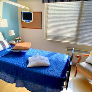 A bright and inviting hospital patient room with a neatly made bed and comfortable seating.