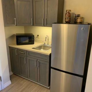 Small kitchen area with a fridge, microwave, and sink.