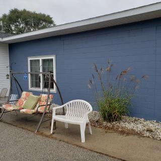 Outdoor seating area with a swing and chair beside a blue wall.