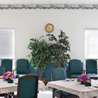 A well-decorated dining area with tables set with flowers and a plant against the wall.