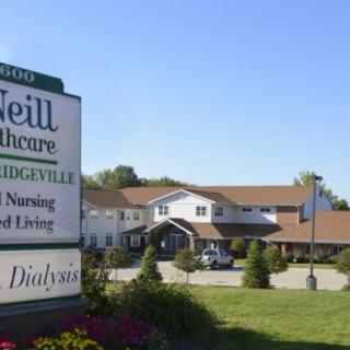 A nursing and assisted living facility with a sign out front in a landscaped area.