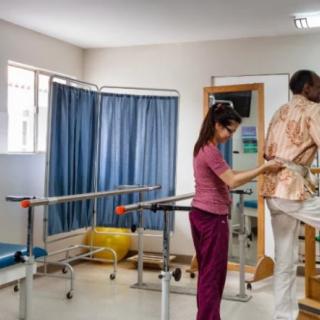A healthcare professional assists a patient with physical therapy exercises in a rehabilitation room.