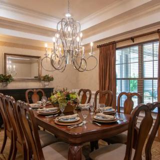 A beautifully arranged dining room featuring an elegant chandelier and a large wooden table set for a meal.