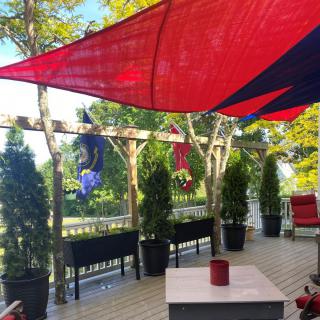 A peaceful outdoor deck with colorful shade sails and potted plants.