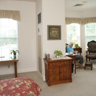 A cozy living room with a person reading by the window, surrounded by elegant furniture and natural light.