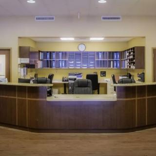 A spacious reception area with a large wooden desk and organized shelves in the background.