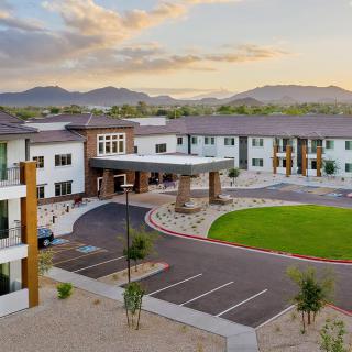 Modern building with a circular driveway set against a mountainous backdrop.