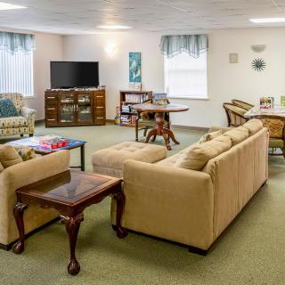 A cozy living room featuring a beige sofa, a coffee table, and a television, with comfortable seating arrangements and various decorative elements.
