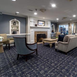 A cozy living room with elegant furniture, featuring a fireplace and a carpeted floor.
