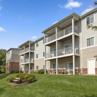 A modern apartment building with multiple balconies and a well-maintained lawn.