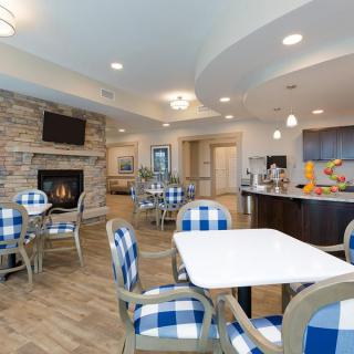 A modern dining area with blue checkered chairs, a fireplace, and a kitchen section.