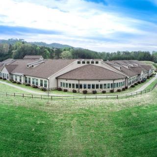 A large building situated in a scenic countryside with a clear blue sky above.