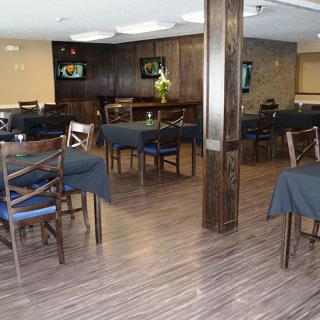 A modern restaurant dining area with wooden flooring and neatly arranged tables and chairs.