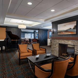 A modern lounge area featuring a fireplace, a grand piano, and comfortable seating.