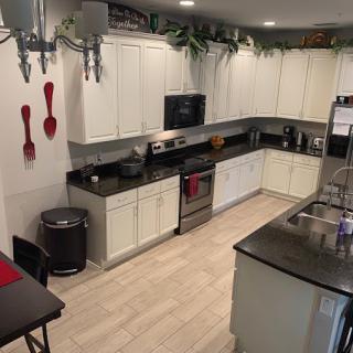 A modern kitchen with white cabinets, black countertops, and red accents.