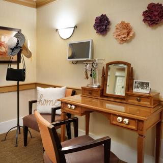 A cozy dressing room with a vanity, mirror, and decorative flowers on the wall.