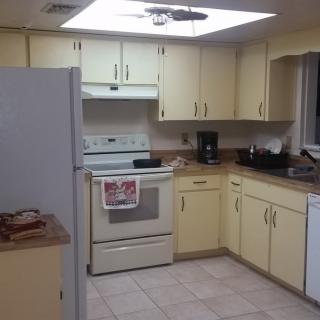 A cozy kitchen with yellow cabinets and essential appliances.