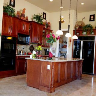 A spacious and modern kitchen featuring elegant wooden cabinetry, a central island, and decorative plants.