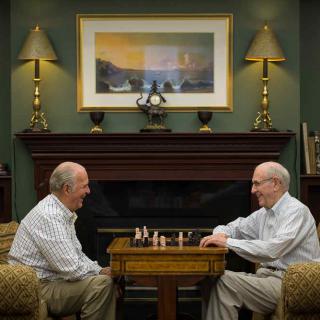 Two senior men enjoying a game of chess in a cozy indoor setting.