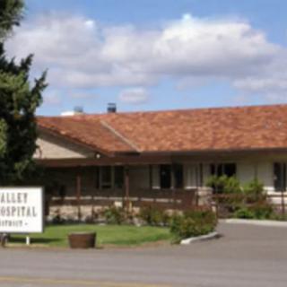 A view of a hospital building with a sign out front on a sunny day.
