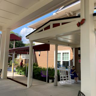 An inviting porch with white rocking chairs in front of a building under a clear blue sky.