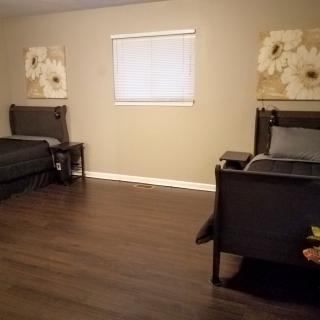 A minimalist bedroom with two twin beds and floral wall art.