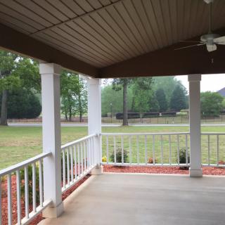 A spacious porch overlooking a green lawn with trees.