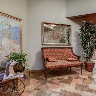 A cozy room with classic decor featuring a patterned bench, large artwork, plants, and a decorative mirror.