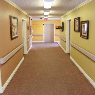 A well-lit hallway with decorative paintings, commonly found in a residential or nursing home.