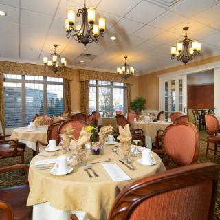 An elegant dining room with beautifully set tables and ornate chandeliers.