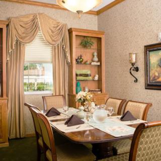 An elegantly decorated dining room with a well-set table, featuring plush curtains and framed artwork.