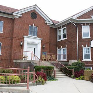 A brick building with a central entrance and stairs leading up to it.