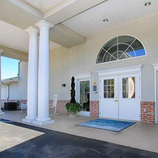 A building entrance featuring white columns and an arched window above double doors.