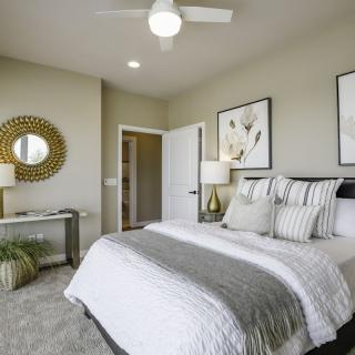 A modern bedroom with a neatly made bed, stylish decor, and contemporary artwork.