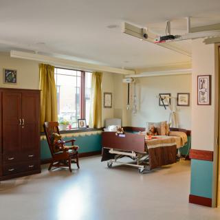 A hospital room with a medical bed, wooden furniture, and decor.