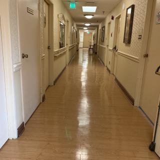 A clean, well-lit hospital corridor with several doors along the hallway.
