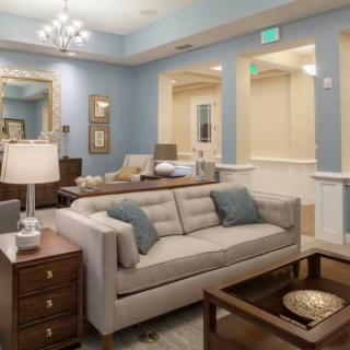 A modern living room with blue walls, featuring a sofa, coffee table, and elegant lighting.