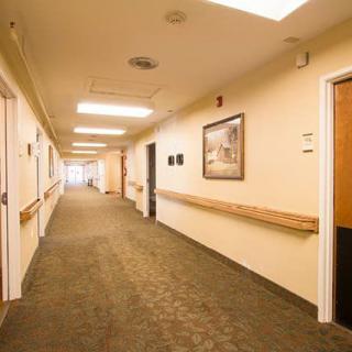 A well-lit hallway with carpet and framed pictures on the walls.