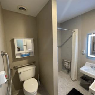A modern bathroom featuring a toilet, sink, and shower with a neutral color scheme.