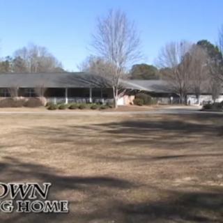 A building surrounded by trees on a grassy area during winter.