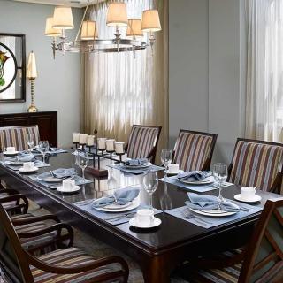 An elegantly set dining room table with striped chairs and a chandelier.