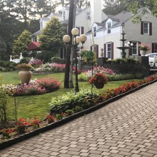 Beautifully landscaped garden with colorful flowers, a fountain, and a charming house in the background.