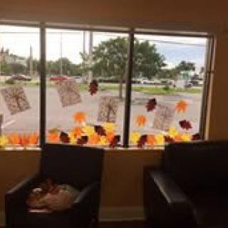 A room with fall-themed decorations on the window, featuring colorful leaves and artwork.
