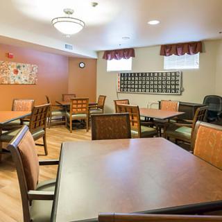 A cozy dining room with multiple tables and chairs, warmly lit and decorated.